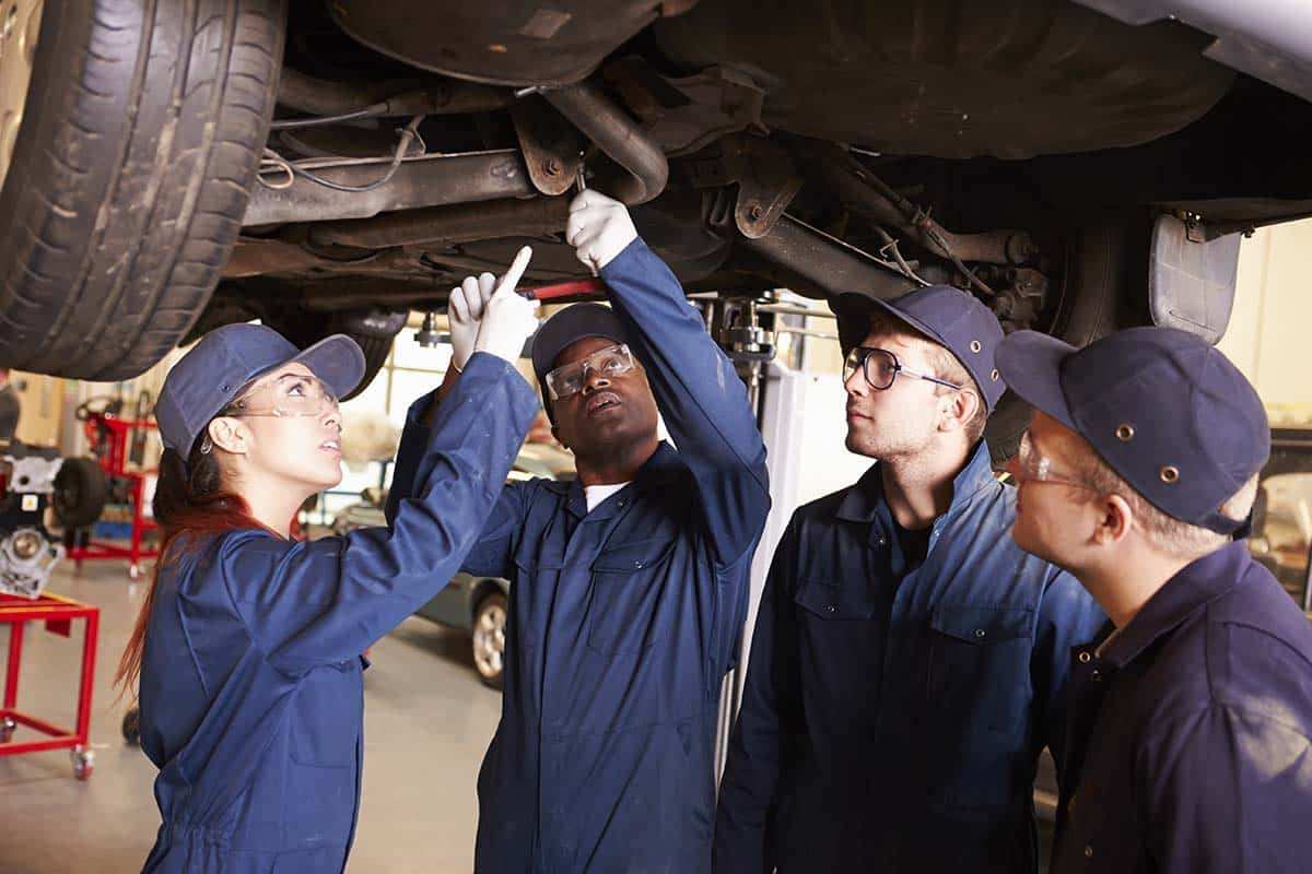 Teacher Helping Students Training To Be Car Mechanics