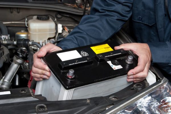 Auto technician mechanic changes battery in car