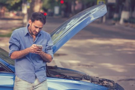 Upset young man calling texting roadside assistance after breaking down